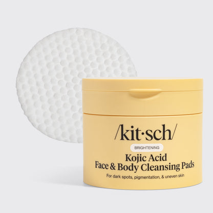 KITSCH Kojic Acid Face & Body Cleansing Pads — hero product shot on light gray background — yellow tub with single white pad displayed — BRIGHTENING | For dark spots, pigmentation, & uneven skin — Kojic Acid helps fade dark spots, reduce sun damage, and lighten acne scars — Turmeric Root Powder fights dullness and boosts antioxidants — Contains 50 pads